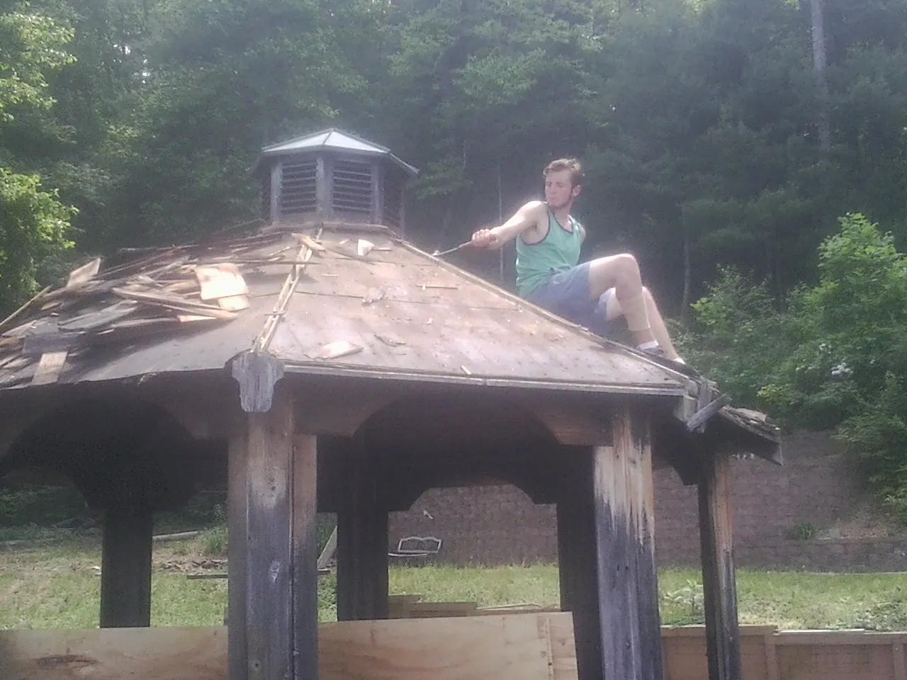 Tearing the old roof off a wooden gazebo before new shakes in Natchez