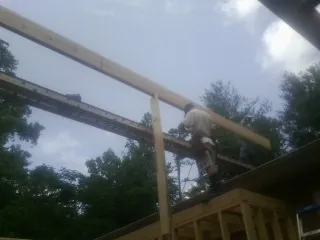 Carpenter setting a ridge beam over a new addition frame — Ice Dam Removal by Roofing Brothers in Natchez