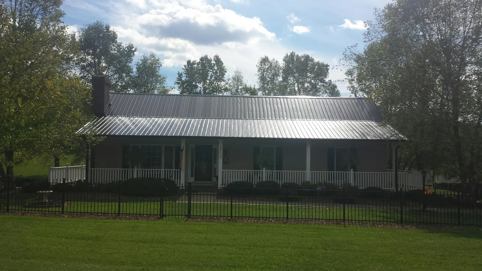 Gray metal roof on a brick ranch with a full width front porch — Gutter Guard Installation work by our crew in Natchez