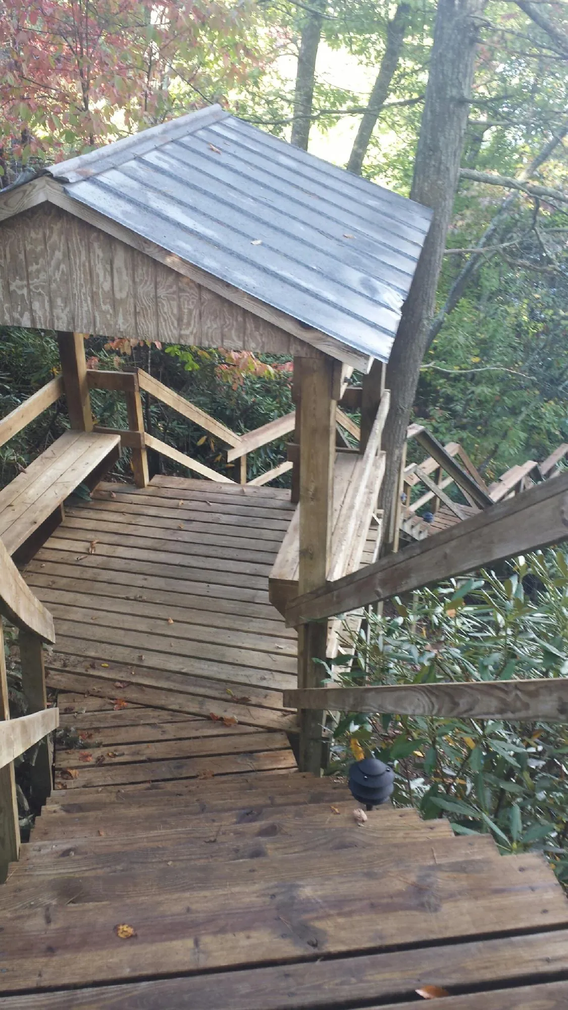 Metal roofed shelter over wooden steps on a wooded walkway — Skylight Repair & Installation work by our crew in Natchez