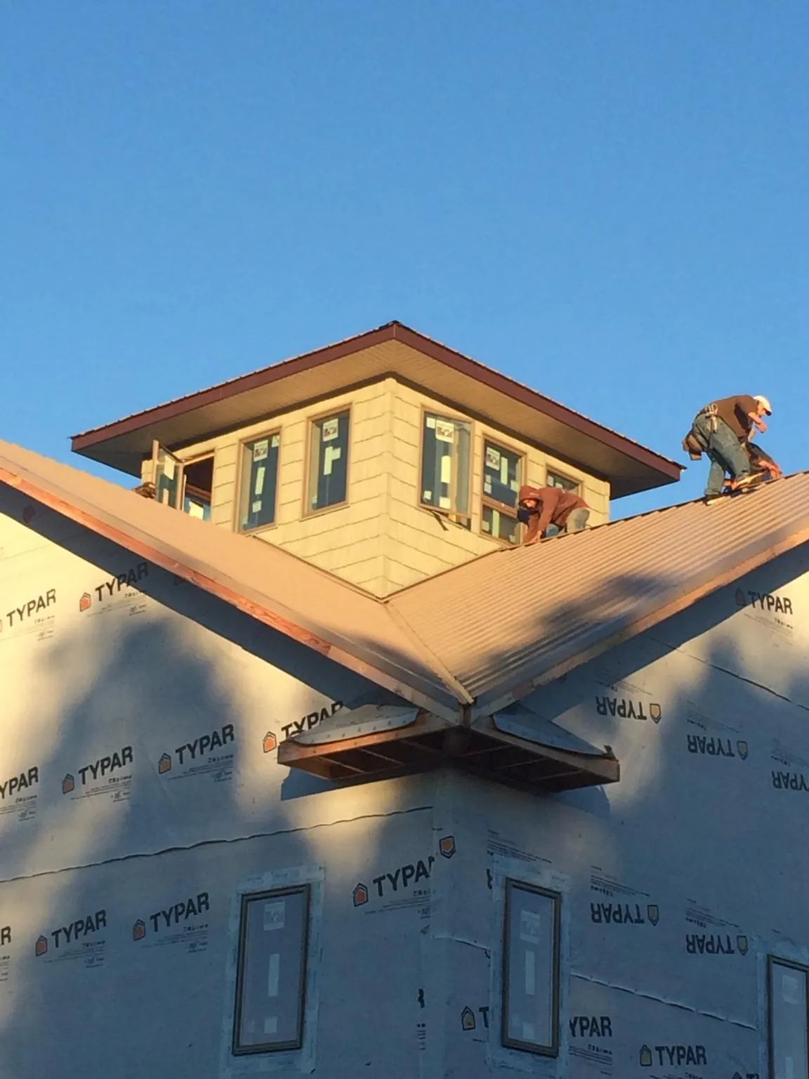 Roofers working around a rooftop cupola on a new metal roof at sunset — Roof Waterproofing in Natchez by Roofing Brothers